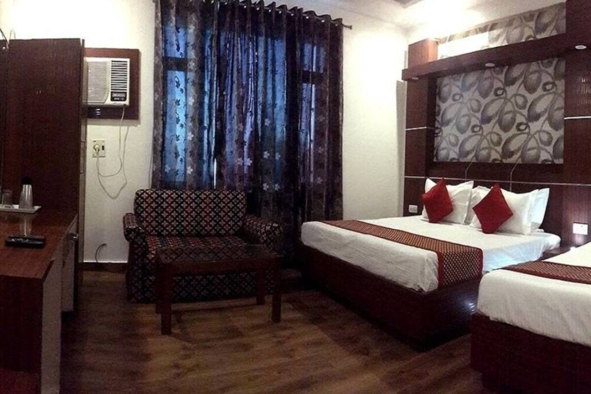Habitación de hotel con dos camas, un escritorio, una silla y una ventana con cortinas.