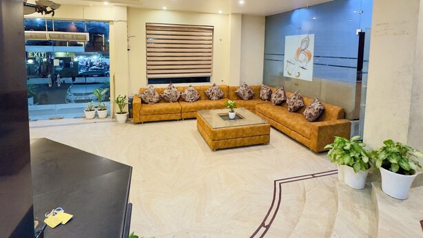 A modern living room with a sectional sofa, a coffee table, and potted plants. - Hotel Jagdish Residency (Reasi)