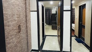 A hotel corridor with a brick wall on the left, a mirrored wall on the right, and a tiled floor. - Hotel Jagdish Residency (Reasi)