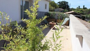 Un espace patio avec un bâtiment blanc, une chaise verte et une petite table.