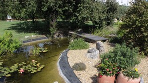 Un jardin avec un étang, un pont en bois et des plantes en pot.