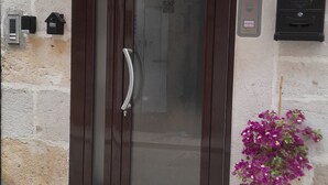 A door with a glass panel and a handle, a small red flower pot with a plant, and a mailbox on the wall. - Il Cavalliere Bed & breakfast (Barletta)