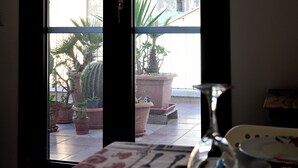 A view through a glass door of a room with a tiled floor, several potted plants, and a table with a glass. - Il Cavalliere Bed & breakfast (Barletta)