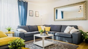 A modern living room with a grey sectional sofa, a white coffee table, and a large mirror on the wall. - Exclusive, spacious and central! (Zagreb)