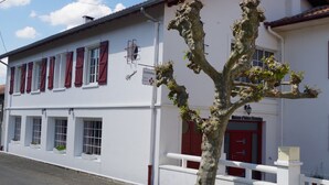 Un edificio blanco con contraventanas y puerta rojas, que dice "Maison d'Hotel Elizondo".