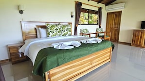 A spacious bedroom with a wooden bed, a green throw, a ceiling fan, and a window with curtains. - Drake Bay Greenleaf (Drake Bay)