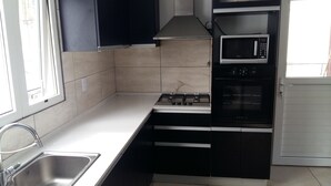 A kitchen with a gas stove, oven, microwave, and stainless steel sink.