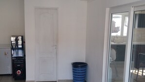 A spacious room with a tiled floor, a white door, a blue laundry basket, and a small appliance unit.