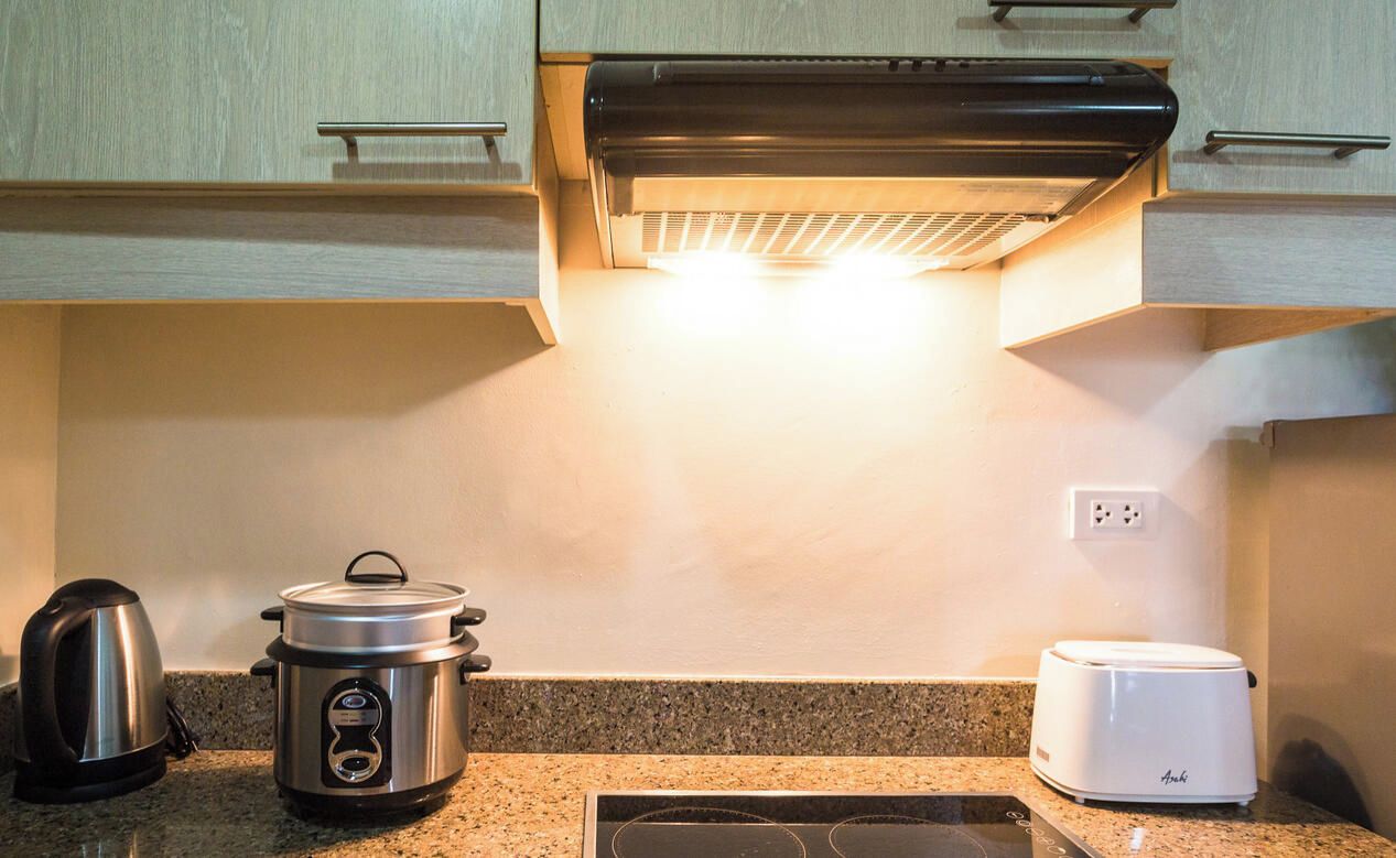 Une cuisine équipée d’une cuisinière, d’un autocuiseur, d’un grille-pain et d’une bouilloire.