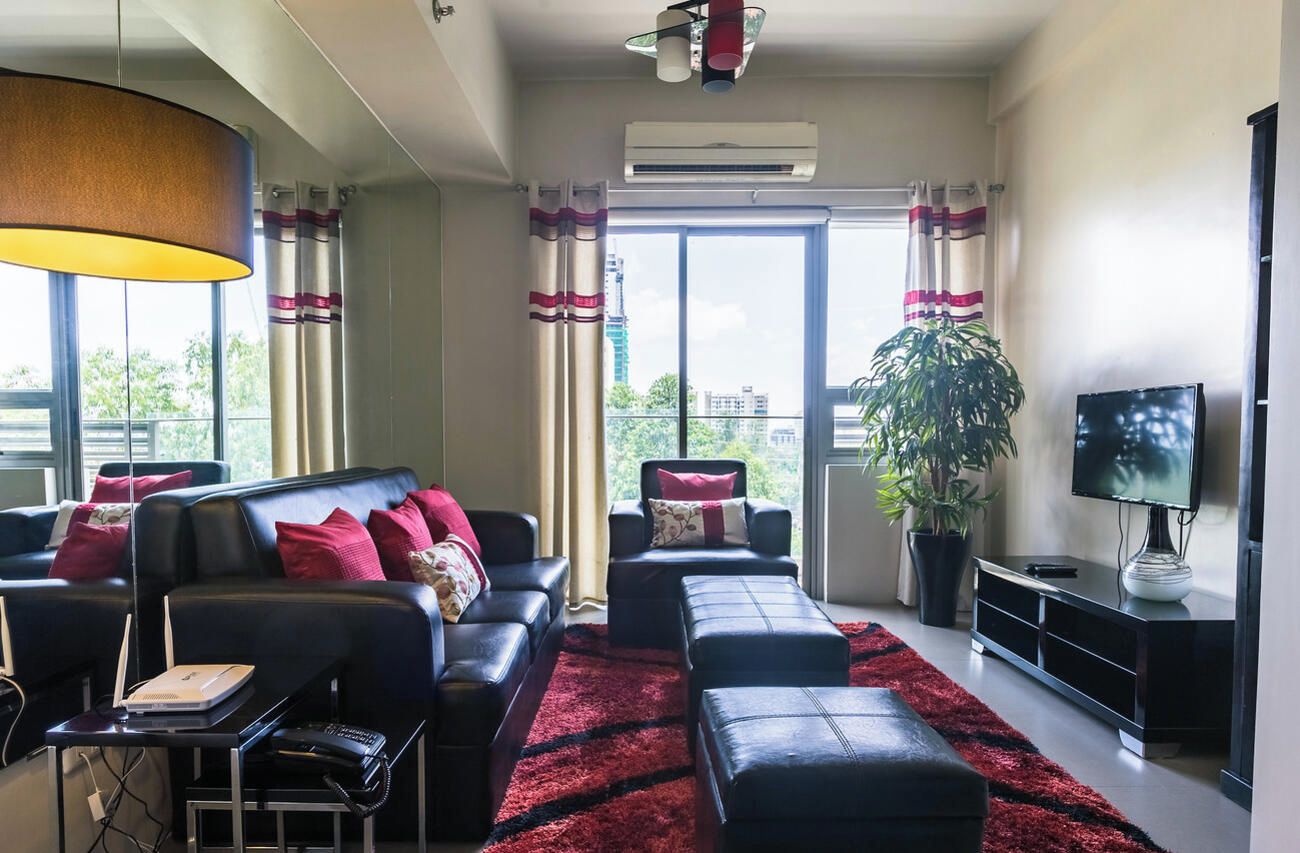 A modern living room with a sofa, ottoman, and a flat-screen TV.