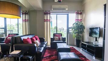 A modern living room with a sofa, ottoman, and a flat-screen TV.