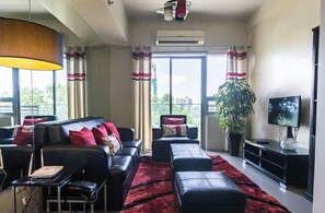 Una sala moderna con un sofá, un reposapiés y un televisor de pantalla plana.