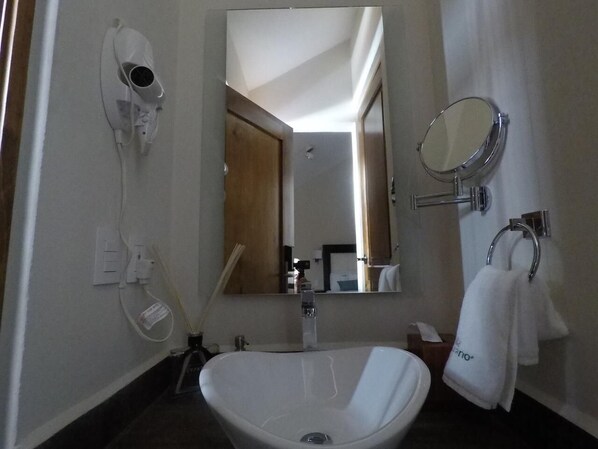 A bathroom with a sink, mirror, towel rack, and hairdryer.