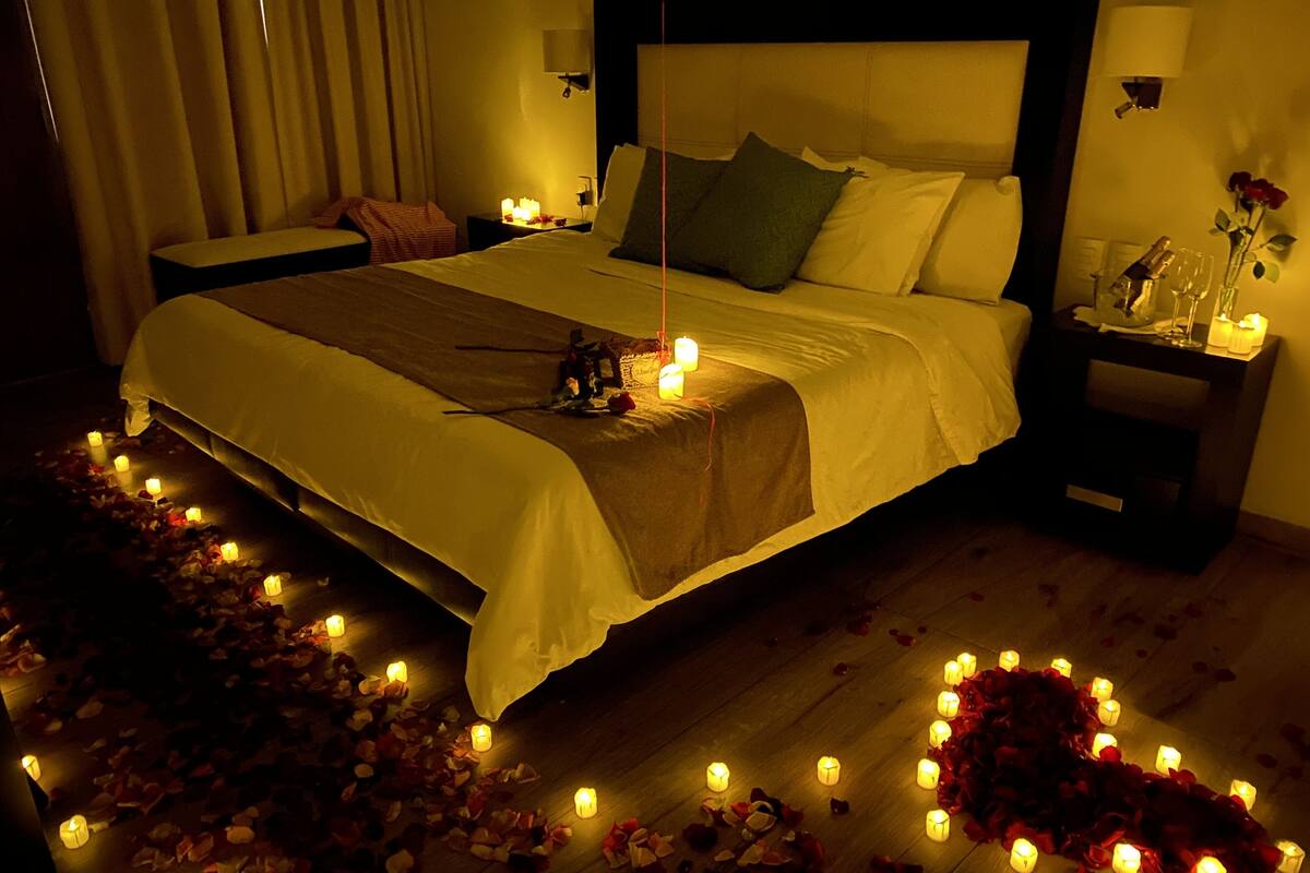 A dimly lit bedroom with a bed, bedside tables, and a nightstand.