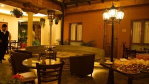 A cozy indoor dining area with round tables, chairs, and hanging plants. - Hotel Villa Murano (San Cristóbal de las Casas)