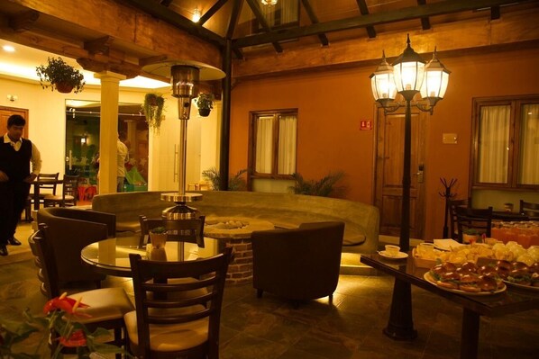 A cozy indoor dining area with round tables, chairs, and hanging plants.