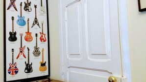 Een poster aan de muur met verschillende gitaren, een piano en een witte deur met een messing deurklink.