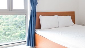 Un dormitorio con un ventanal grande, una cama con ropa de cama blanca y un cabecero de madera.