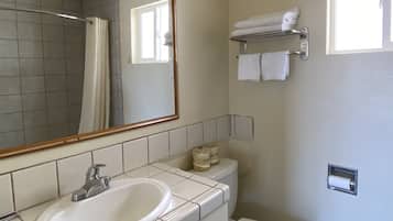 Une salle de bain équipée d’un lavabo, d’un miroir, de toilettes, d’un porte-serviettes et d’une fenêtre.