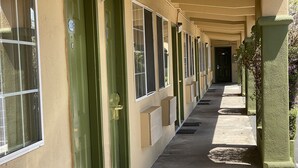 A corridor with green doors, a covered walkway, and a row of windows. - Holiday Motel (Morgan Hill)
