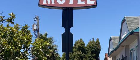 Letrero de motel con diseño clásico, que incluye un gran cartel y una flecha direccional.