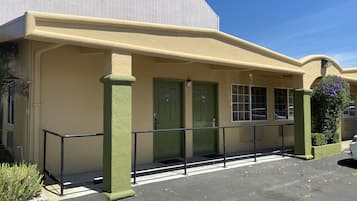 A building with a flat roof, green doors, and a balcony with a railing.