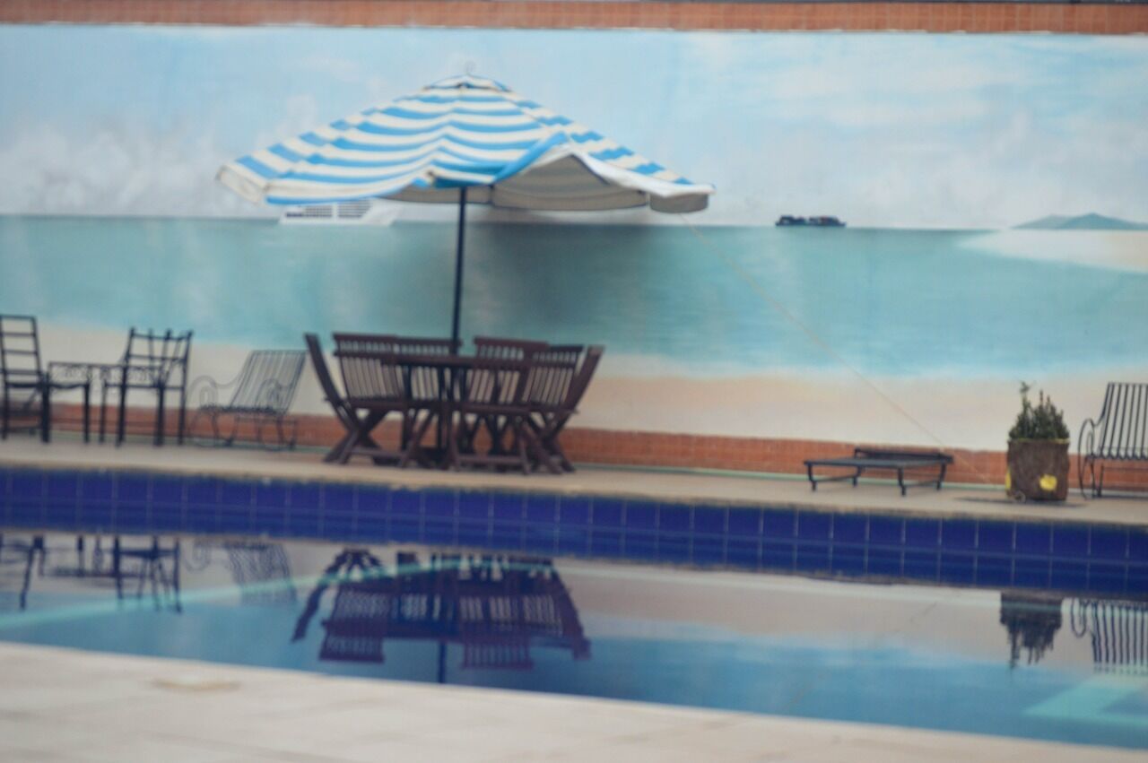 Una piscina con sillas de descanso y una sombrilla.