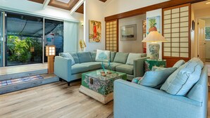 A modern living room with a sectional sofa, a glass coffee table, and a traditional Japanese shoji screen.