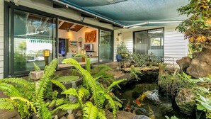 A modern house with a koi pond, indoor plants, and a glass door leading to a living area.