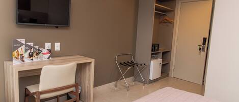 A bedroom with a bed, a desk, a chair, a TV, and a wardrobe.