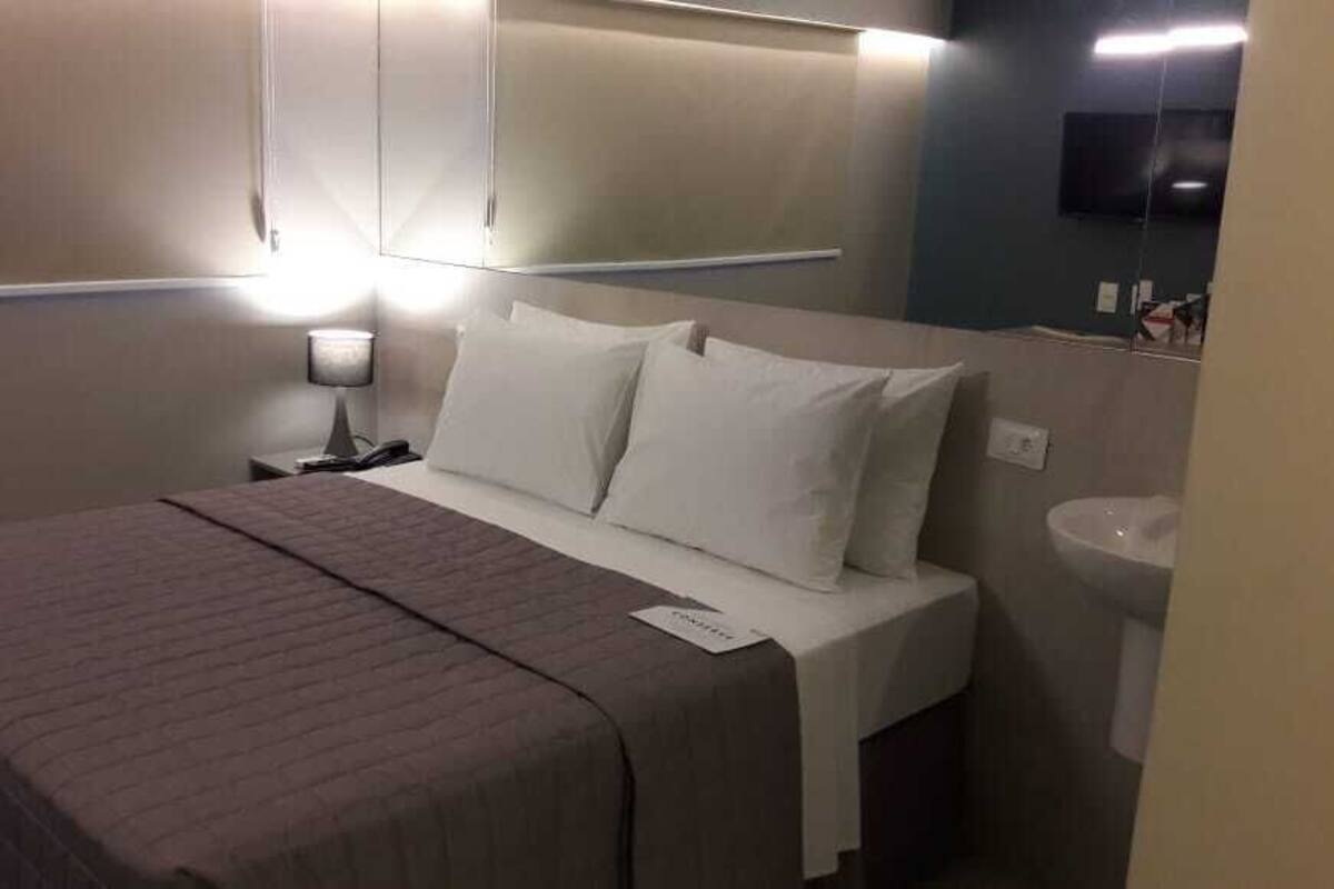 A hotel room with a bed, bedside lamp, and a mirror.