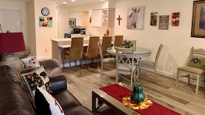 A modern living room with a brown leather couch, a glass coffee table with a red runner, and a dining area with a glass table and chairs. - Walk in level. 3 King beds, , massage chair. Water Bubble Cascade . (Branson)