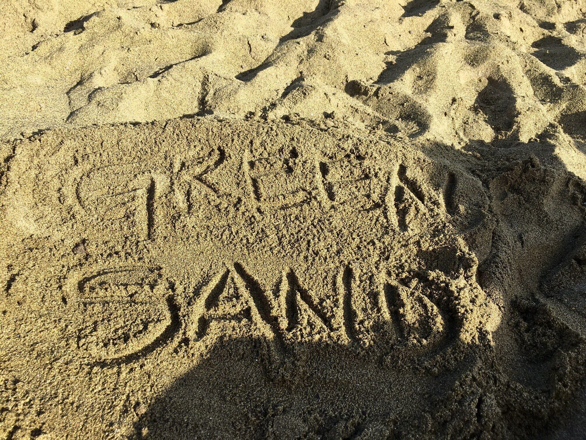 A sandy beach with the words "TRINITY SAN DIEGO" etched into the sand.