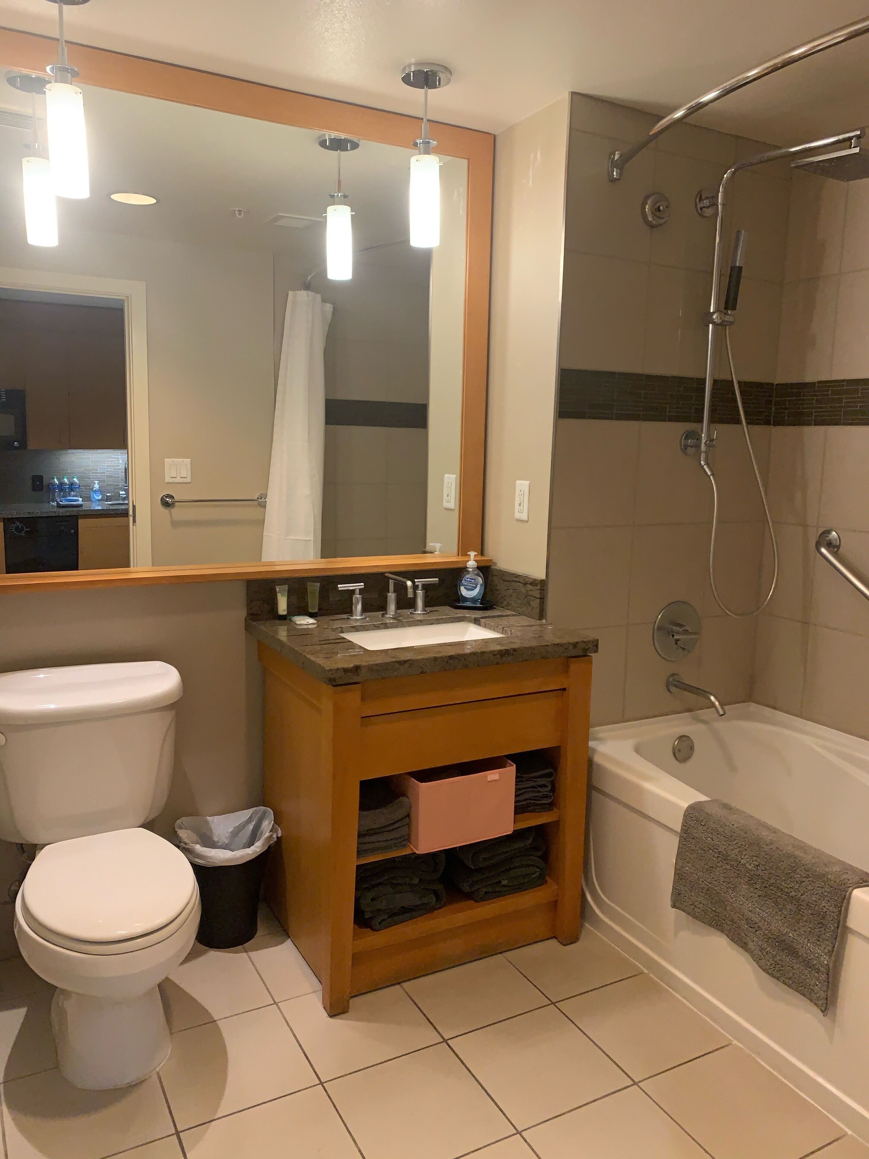 Een badkamer met toilet, wastafel, spiegel, douche en een handdoekrek.