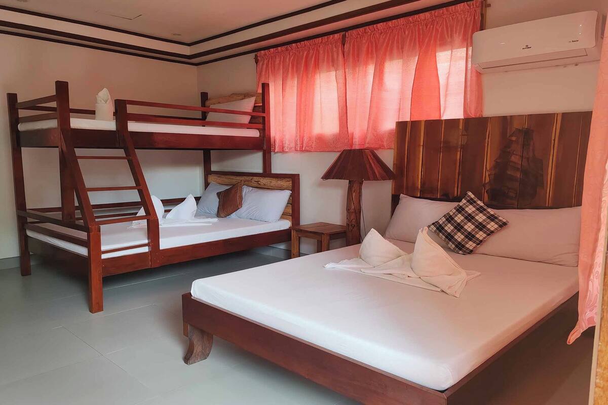 Una habitación con literas, una cama individual, una lámpara y aire acondicionado.