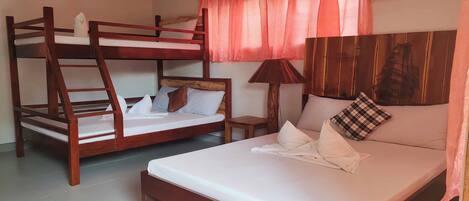 A room with bunk beds, a single bed, a lamp, and an air conditioner.