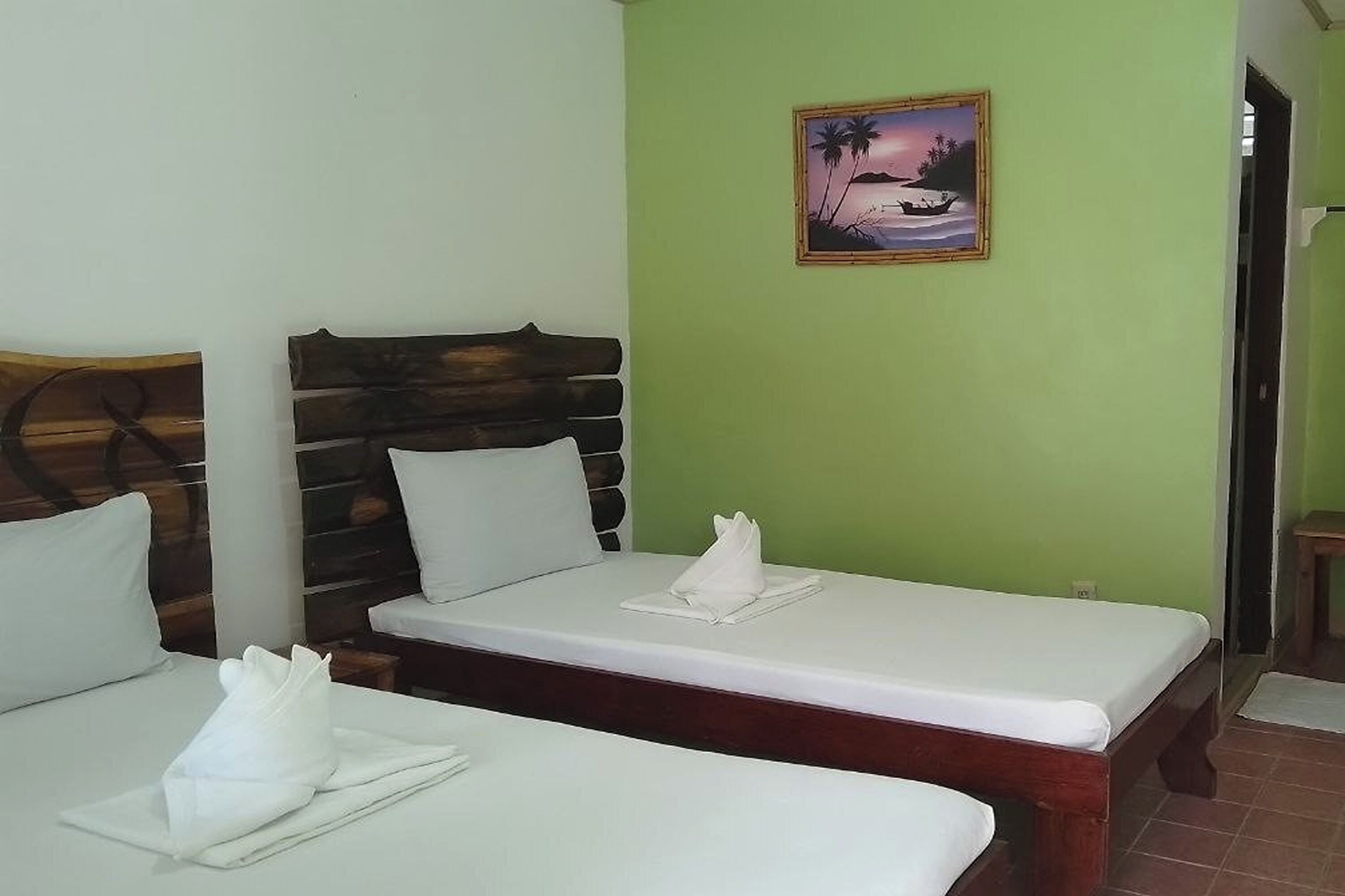 Habitación con dos camas, cada una con cabecero de madera y ropa de cama blanca.