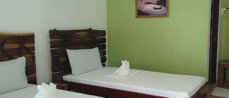 A room with two beds, each with a wooden headboard and white bedding.