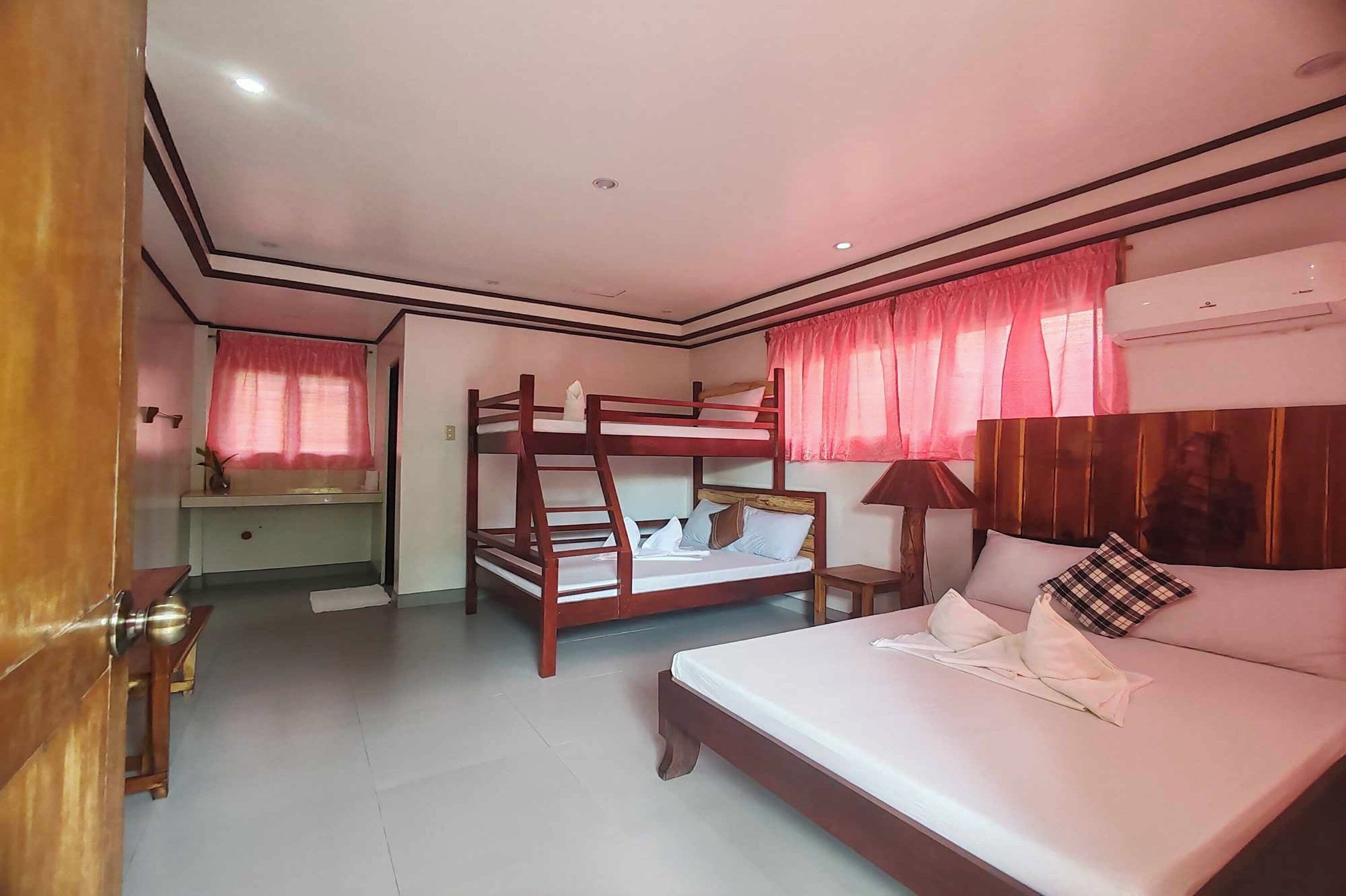 Un dormitorio con literas, una cama individual, un escritorio y un equipo de aire acondicionado.