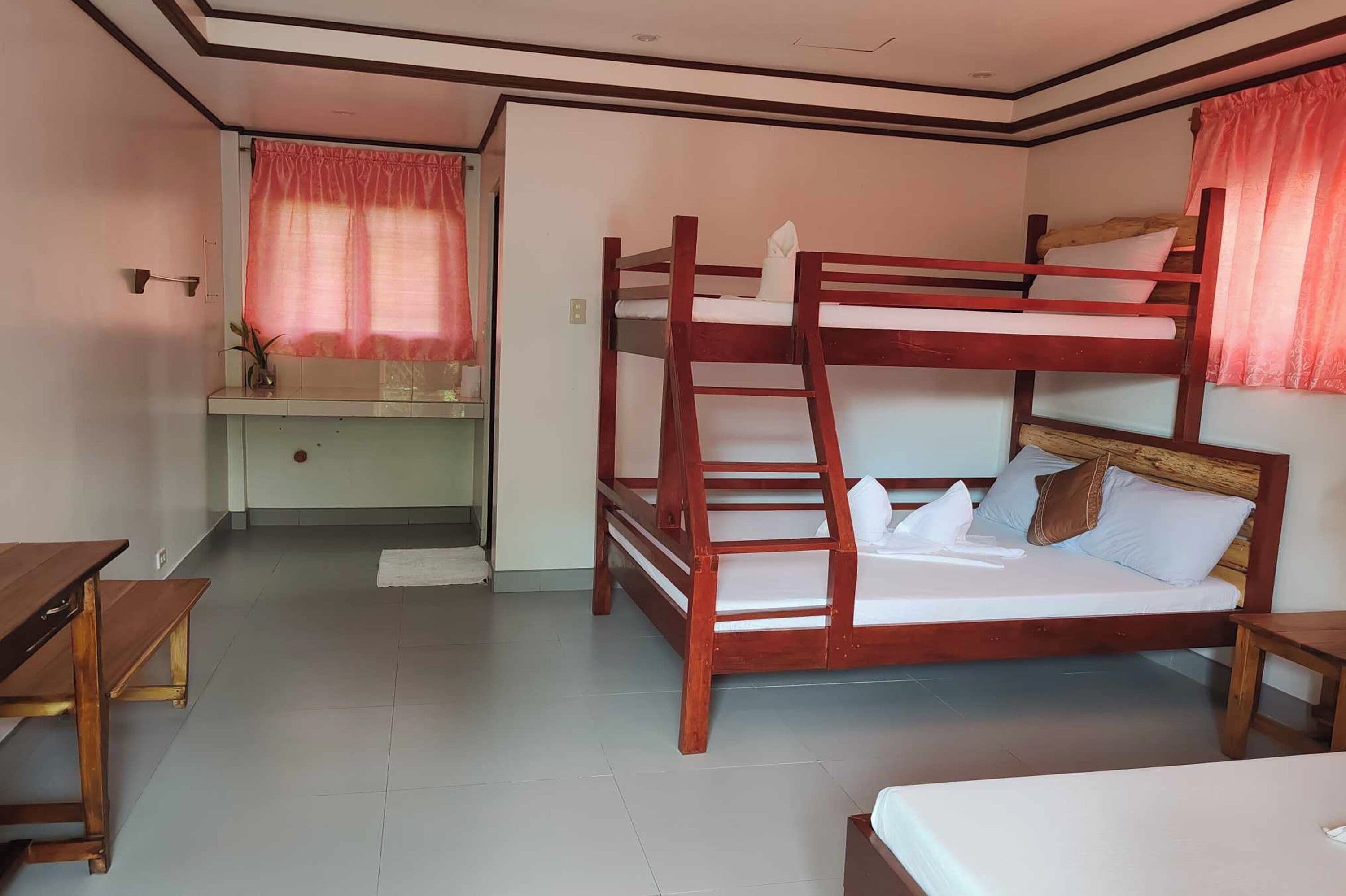A bunk bed room with a desk and a small table.