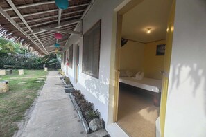 A covered walkway with a bench, a bed, and a door leading to a room. - Summer Homes Beach Front Resort and Cottages Port Barton (San Vicente)
