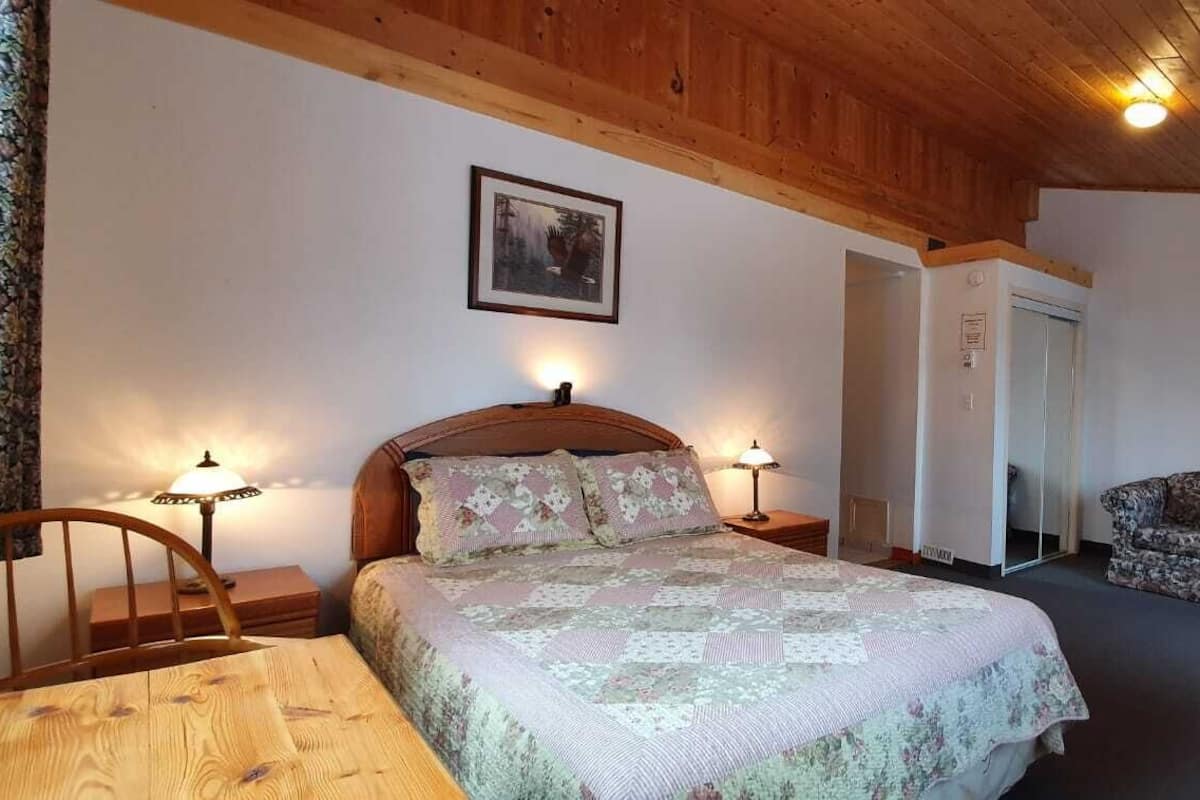 A bedroom with a bed, a nightstand, a chair, a sofa, and a wardrobe.