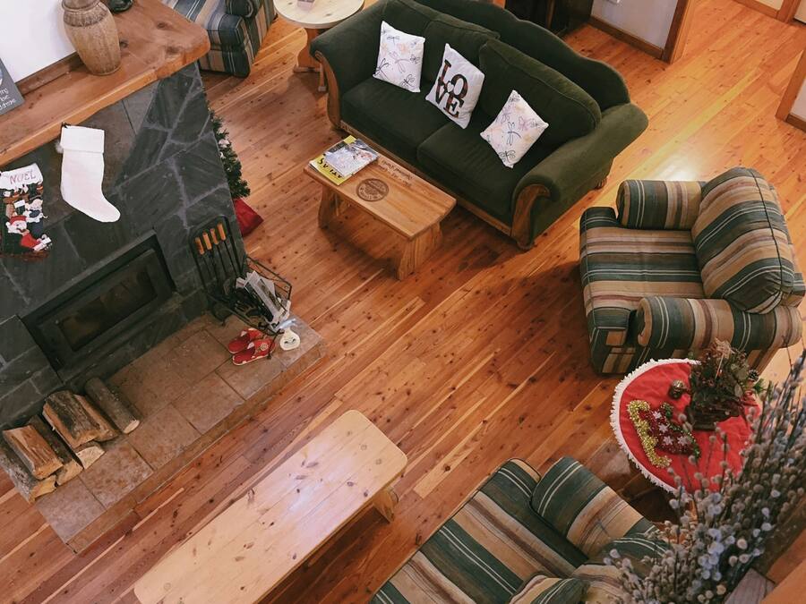Un salon chaleureux avec une cheminée, un canapé vert, des fauteuils à rayures et une table basse en bois.