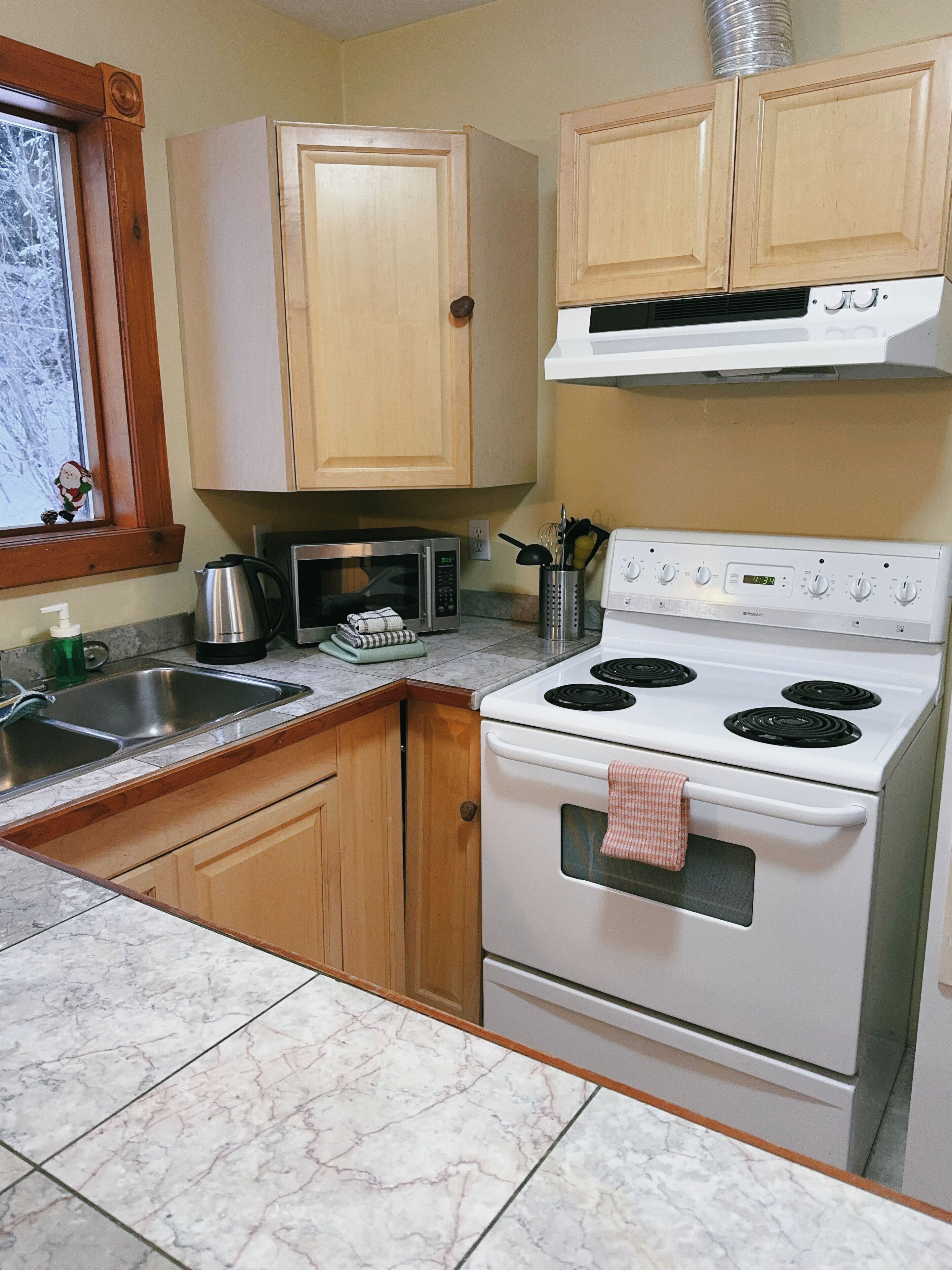 A kitchen with wooden cabinets, a microwave, a stove, and a sink.