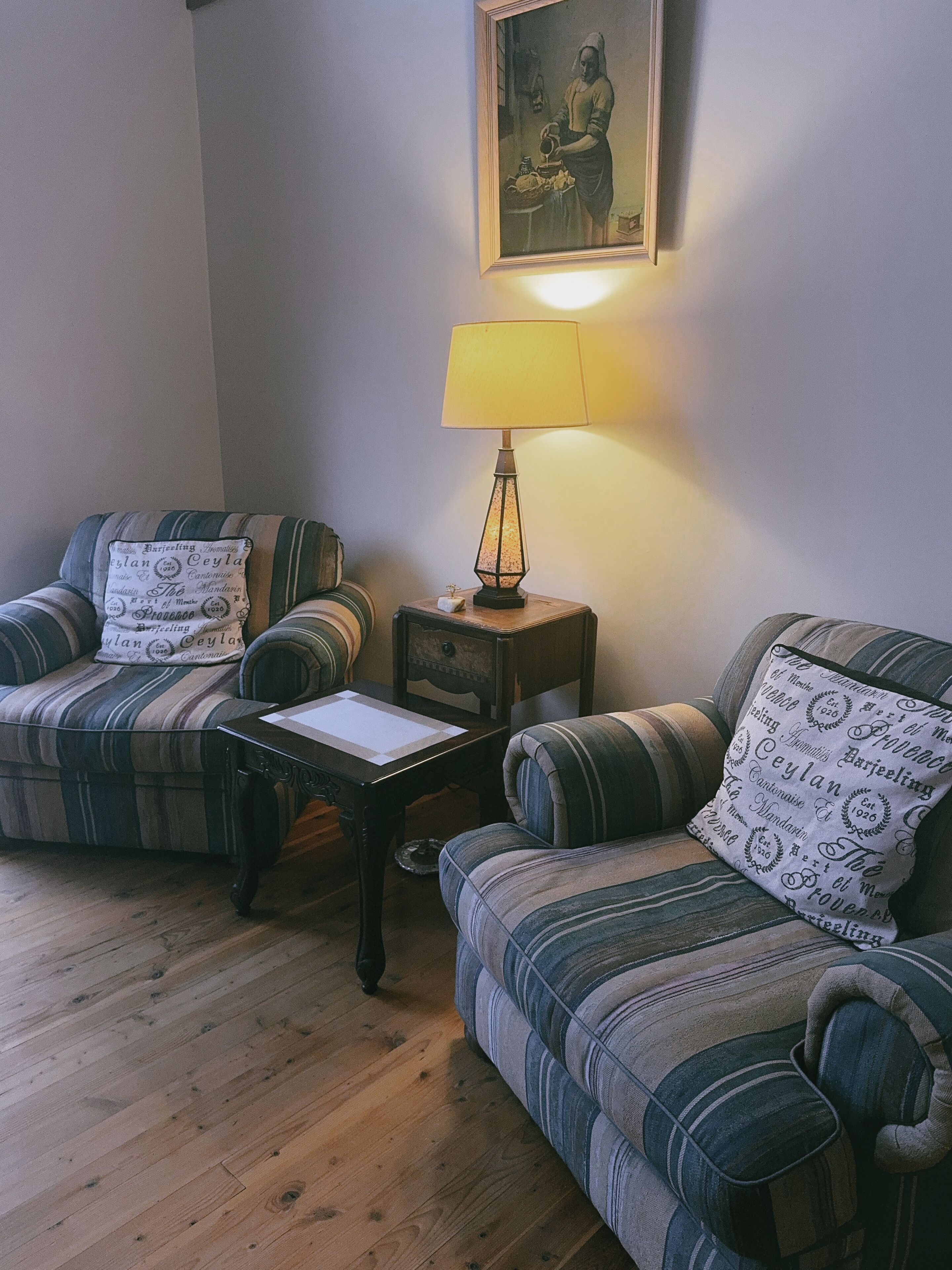 Ein gemütliches Wohnzimmer mit gestreiften Sofas, einem kleinen Holztisch und einer Lampe.