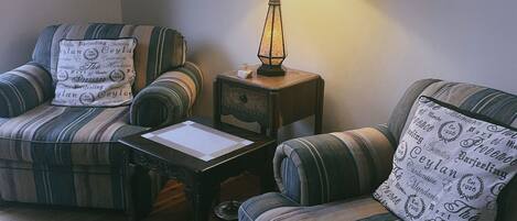 Ein gemütliches Wohnzimmer mit gestreiften Sofas, einem kleinen Holztisch und einer Lampe.