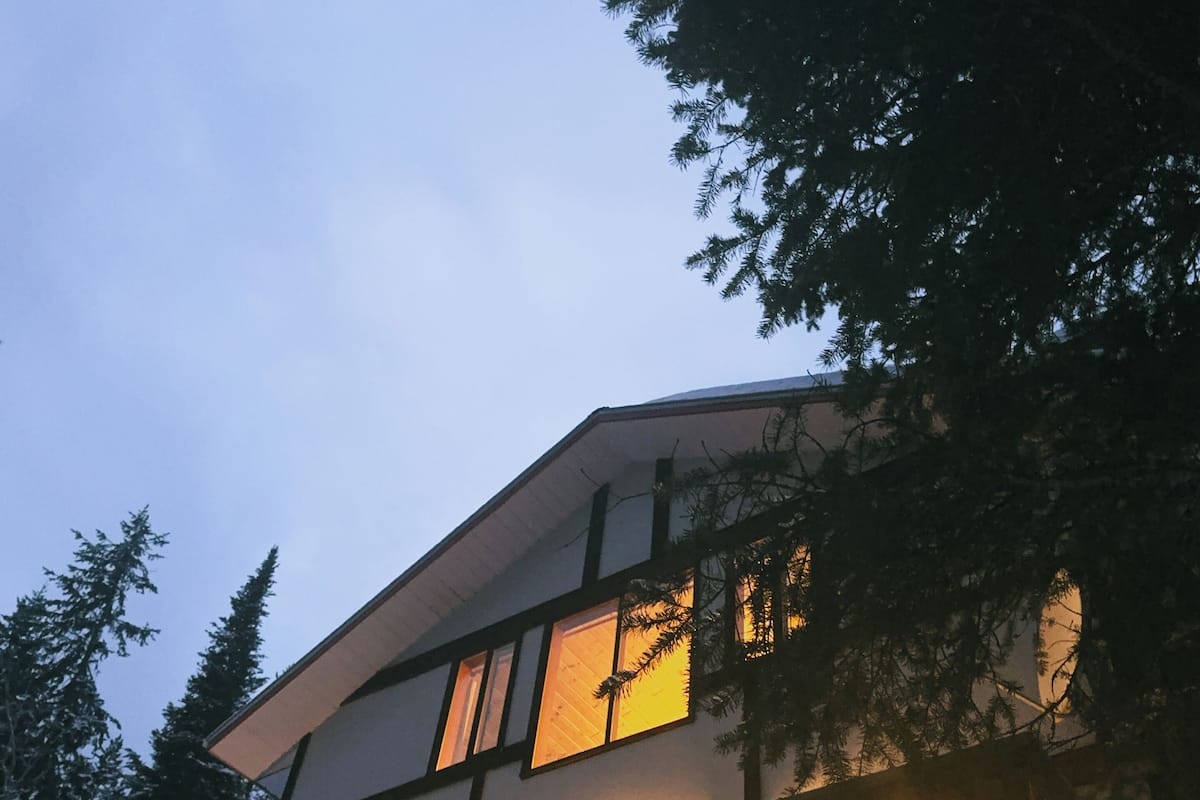 A modern two-story house with large windows, a balcony, and a view of the sky.
