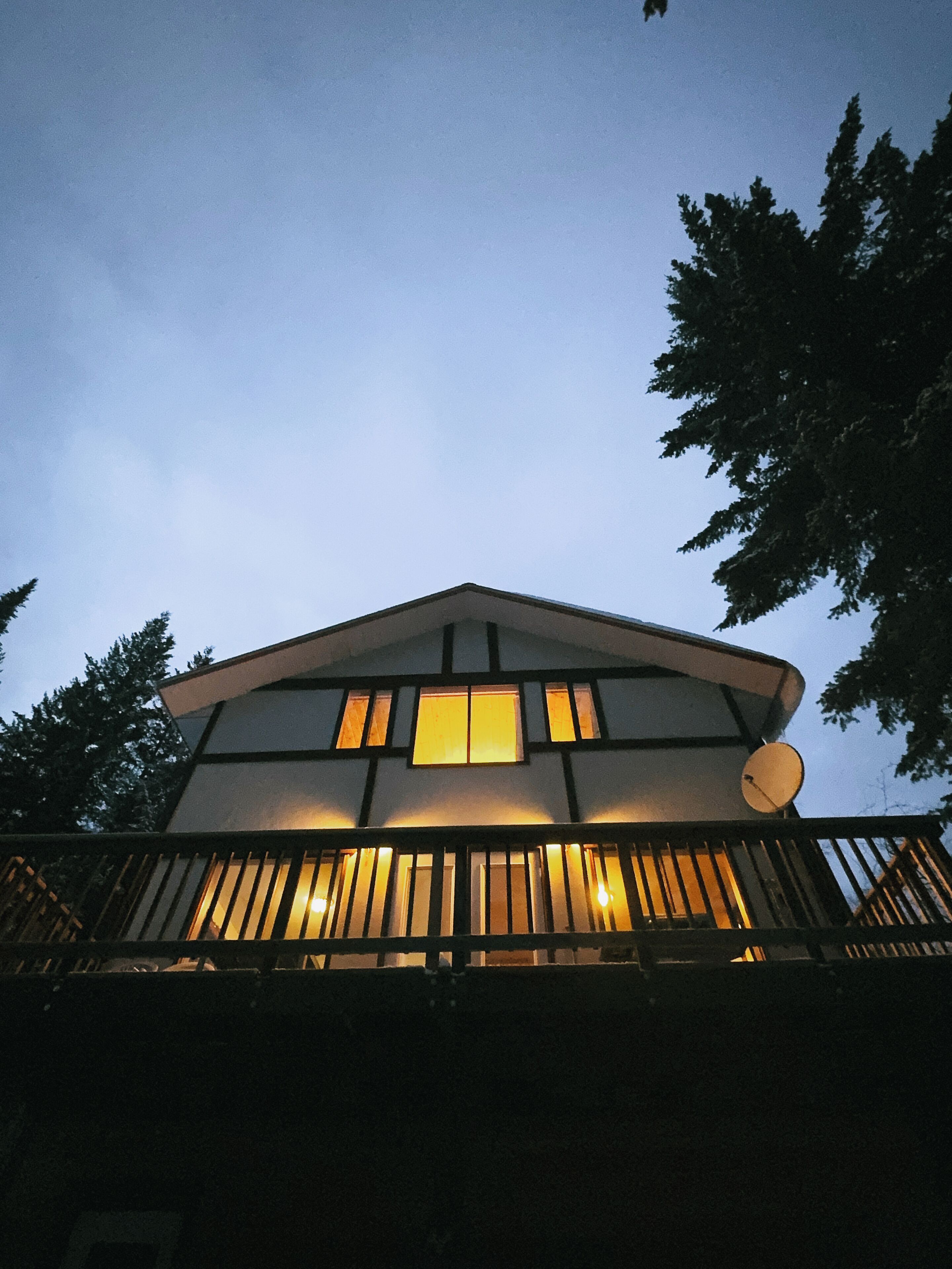A modern house with a sloped roof, large windows, and a satellite dish.
