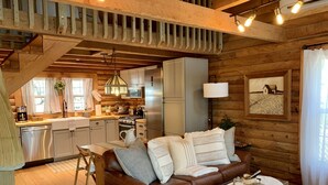 A cozy cabin interior with a wooden interior, a dining area, a kitchen, and a living room with a leather sofa and a coffee table.