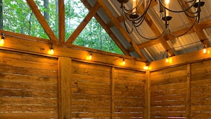 A wooden spa room with a hot tub, wooden walls, and string lights.